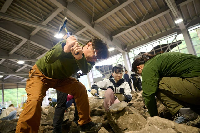 手本を見せる教員は、熟練の技で力強くハンマーを振り下ろし、硬い石を削っていた