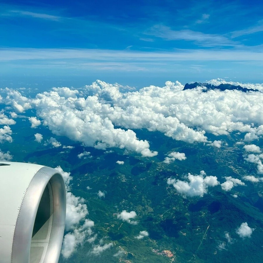 サンダカンに向かう飛行機からの景色。眼下にはジャングル。写真右上に映っている雲海を突き抜けた山は、東南アジア最高峰のキナバル山（標高4095m）。富士山より高い。