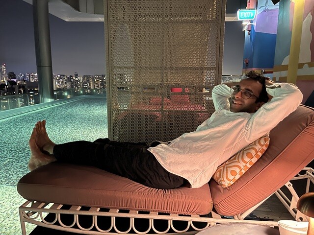 ルーフトップバーのプールサイドにあるサンベッドに寝そべるラヴィ。